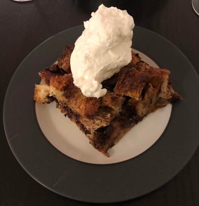 Chocolate bread pudding with whipped cream on a plate